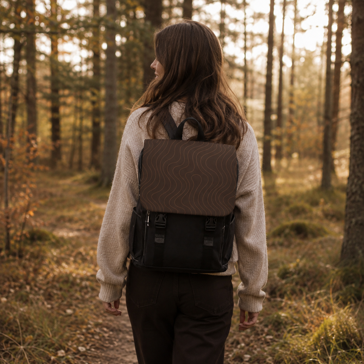 Braun-schwarzer Tagesrucksack Mocha Waves mit Wellenmuster auf dem Rücken eines Models im herbstlichen Wald.
