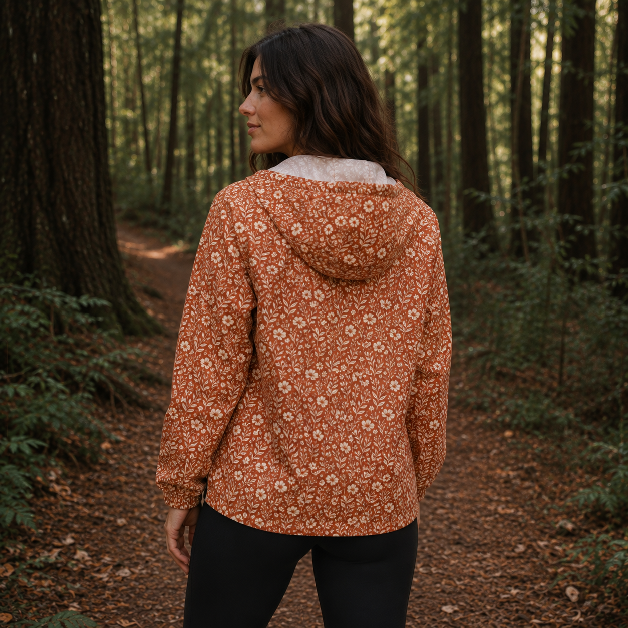 Windbreaker Canyon Bloom für Damen mit terracottafarbenem Blumenmuster, Kapuze und schwarzen Taschen.