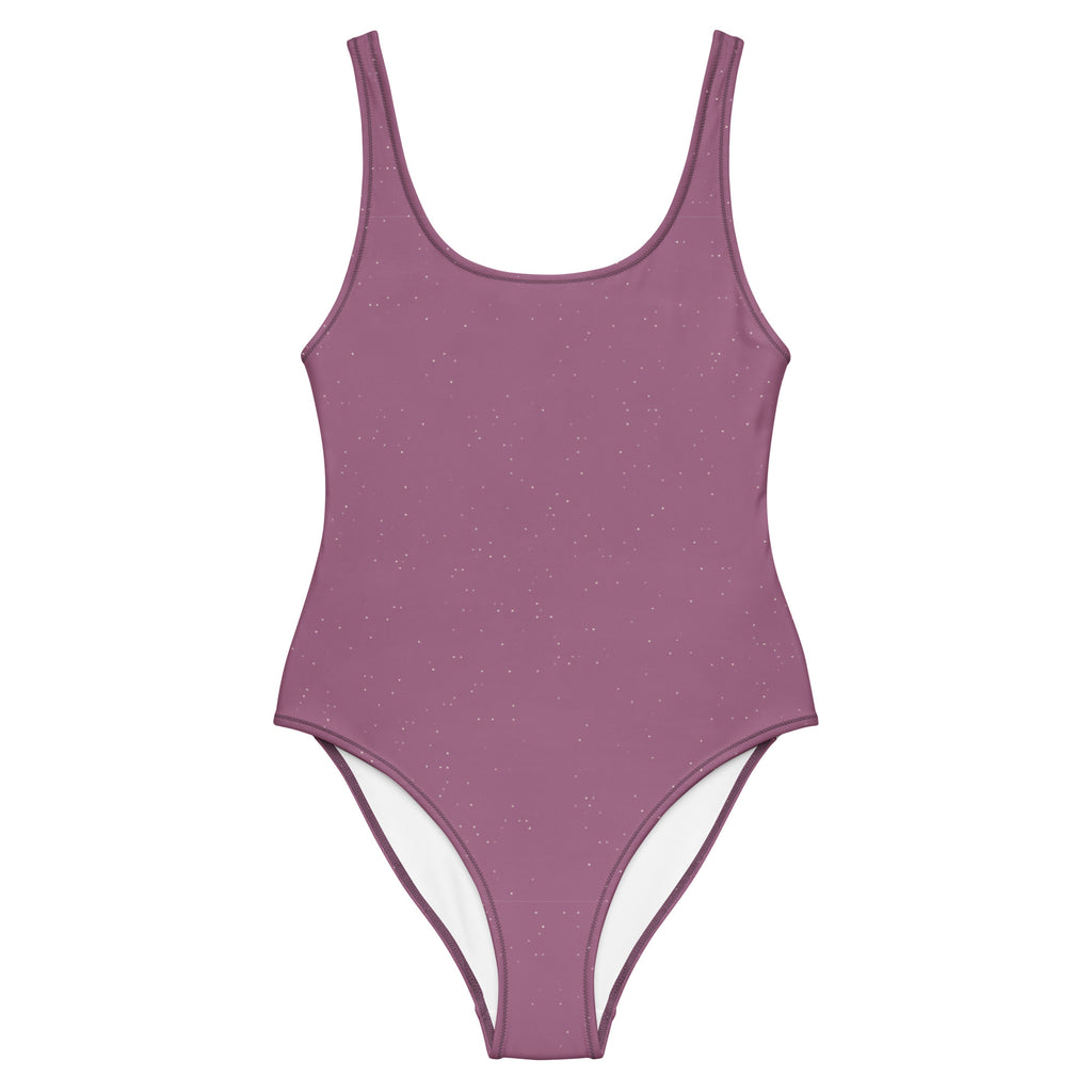 Mauvefarbener Damenbadeanzug Mauve Stardust mit Rundhalsausschnitt, breiten Trägern und dezenten Glitzerakzenten, präsentiert vor türkisblauem Meer und einer mediterranen Steinterrasse mit roten Rosen.