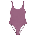 Mauvefarbener Damenbadeanzug Mauve Stardust mit Rundhalsausschnitt, breiten Trägern und dezenten Glitzerakzenten, präsentiert vor türkisblauem Meer und einer mediterranen Steinterrasse mit roten Rosen.