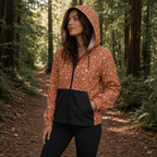 Windbreaker Canyon Bloom für Damen mit terracottafarbenem Blumenmuster, Kapuze und schwarzen Taschen.