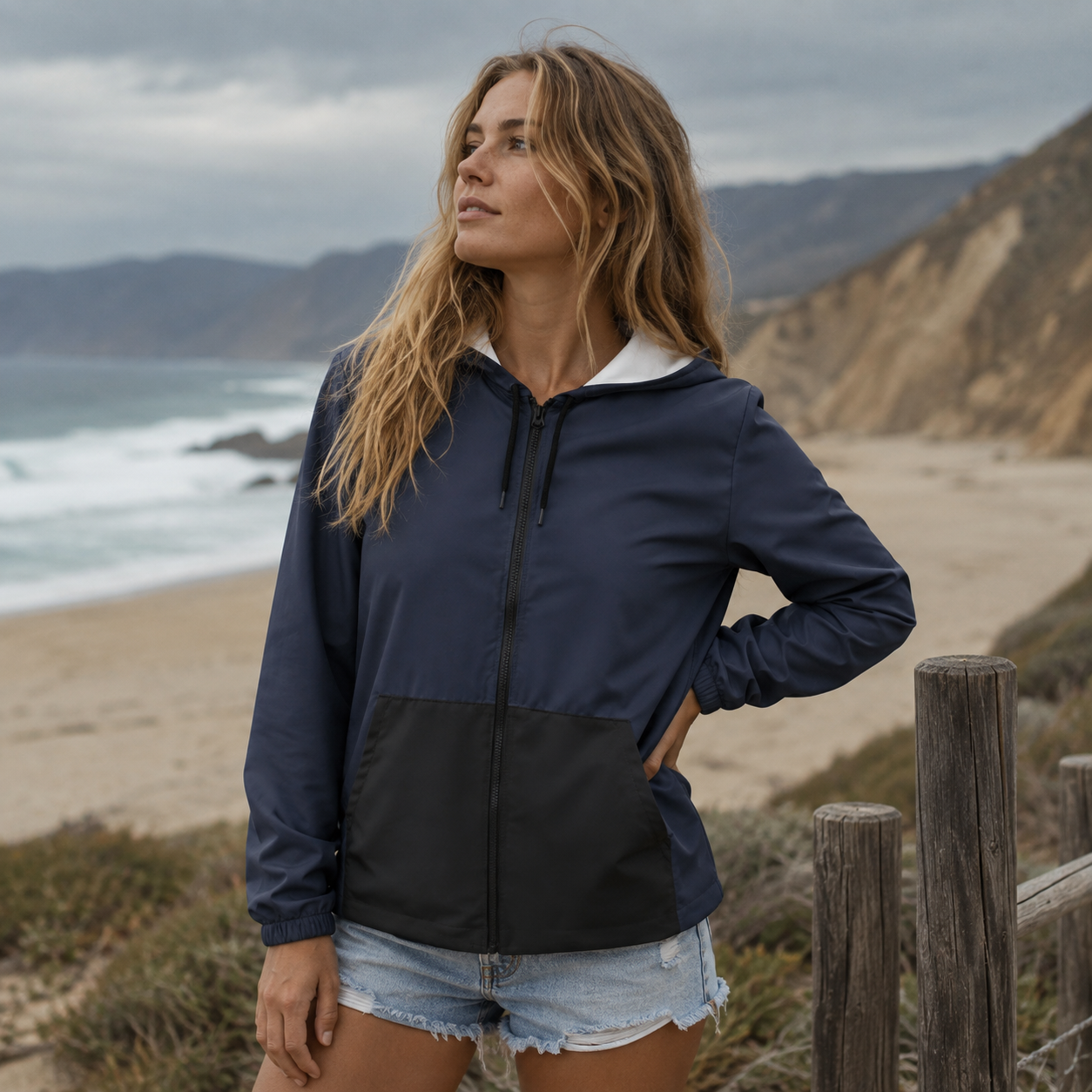 Windbreaker Midnight Blue für Damen in Dunkelblau mit schwarzer Kängurutasche, Kapuze und schwarzem Reißverschluss.